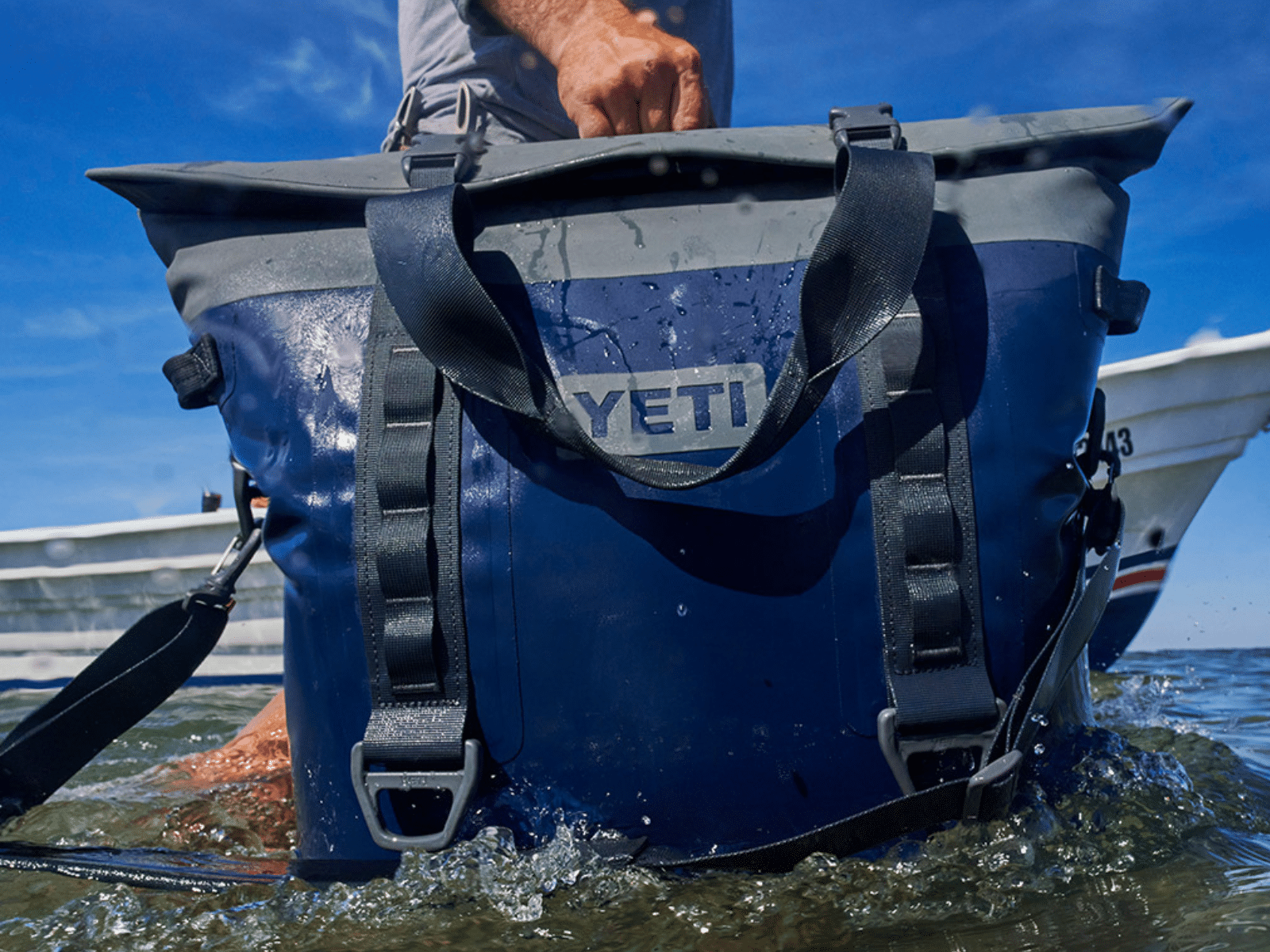 The Yeti Hopper M30 soft cooler tote in navy being carried off a boat