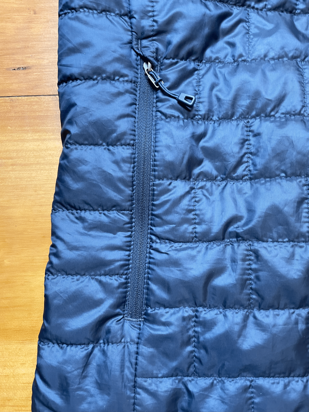 Closeup image of the Patagonia Nano Puff jacket handwarmer pocket zipped closed.