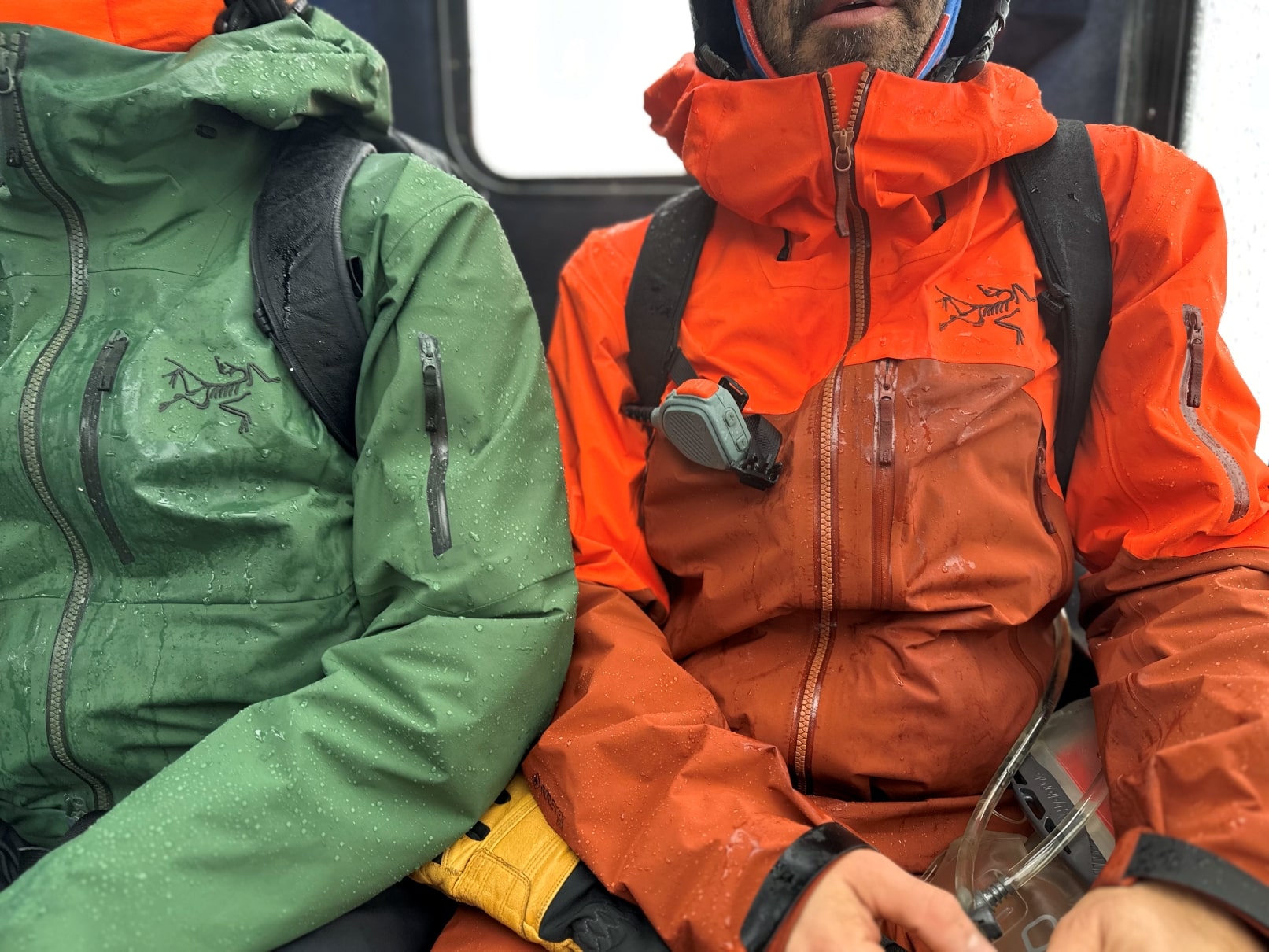 Two snowboarders sitting in a snowcat wearing Arc'teryx jackets