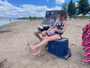 A child sitting lakeside on the YETI Hopper Flip 18 soft cooler.