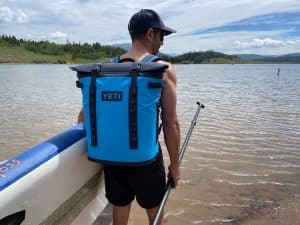 Wearing the YETI Hopper m20 backpack cooler on the shore of a lake.