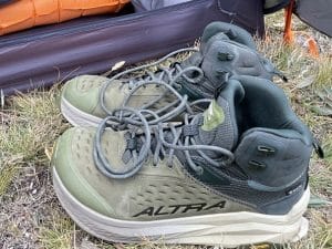 A closeup image of a pair of Altra Olympus 6 Hike Mid GTX boots outside of a backpacking tent.