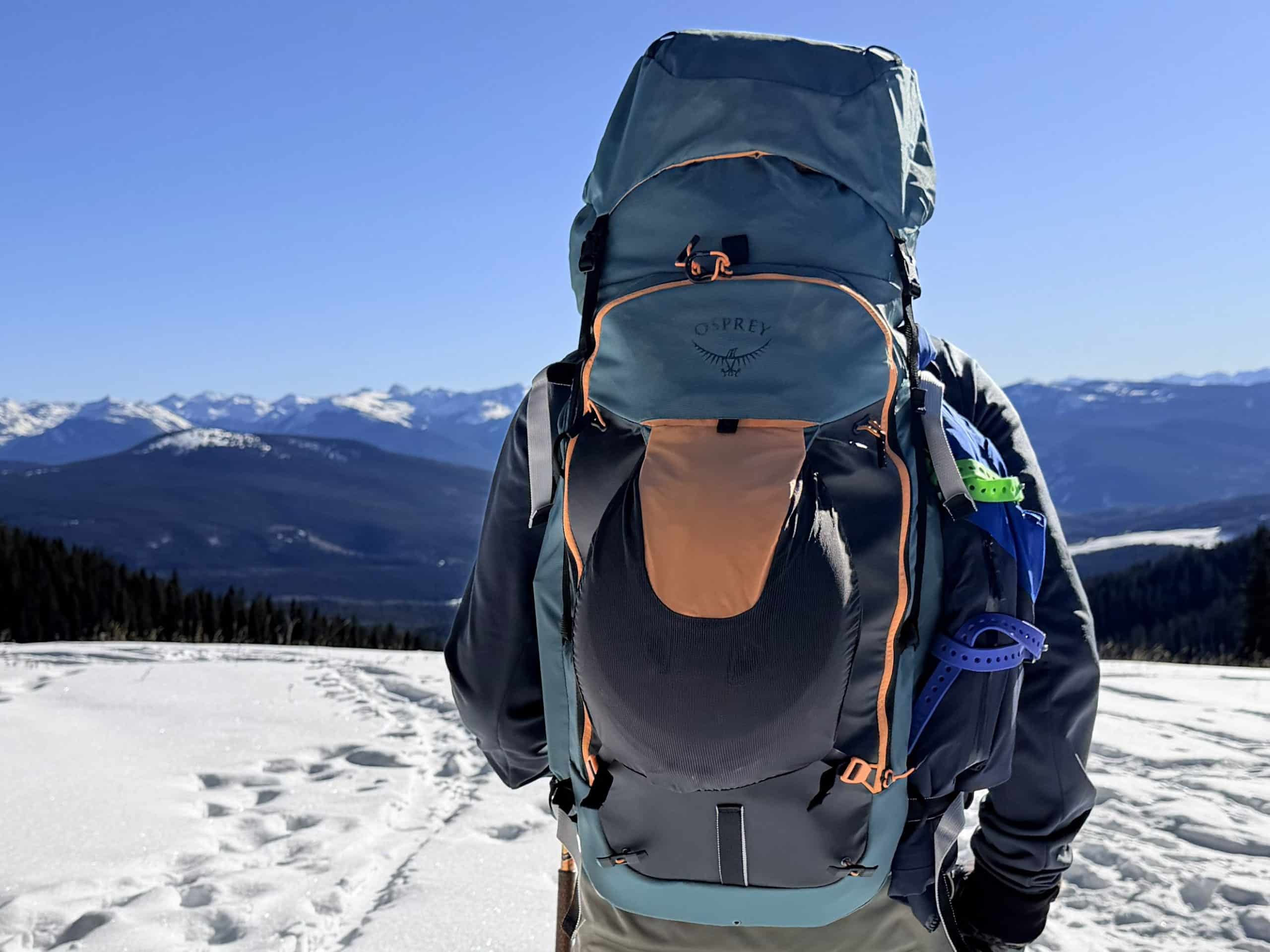 A skier wearing the Osprey Soelden 45L ski pack while looking at a mountain vista.